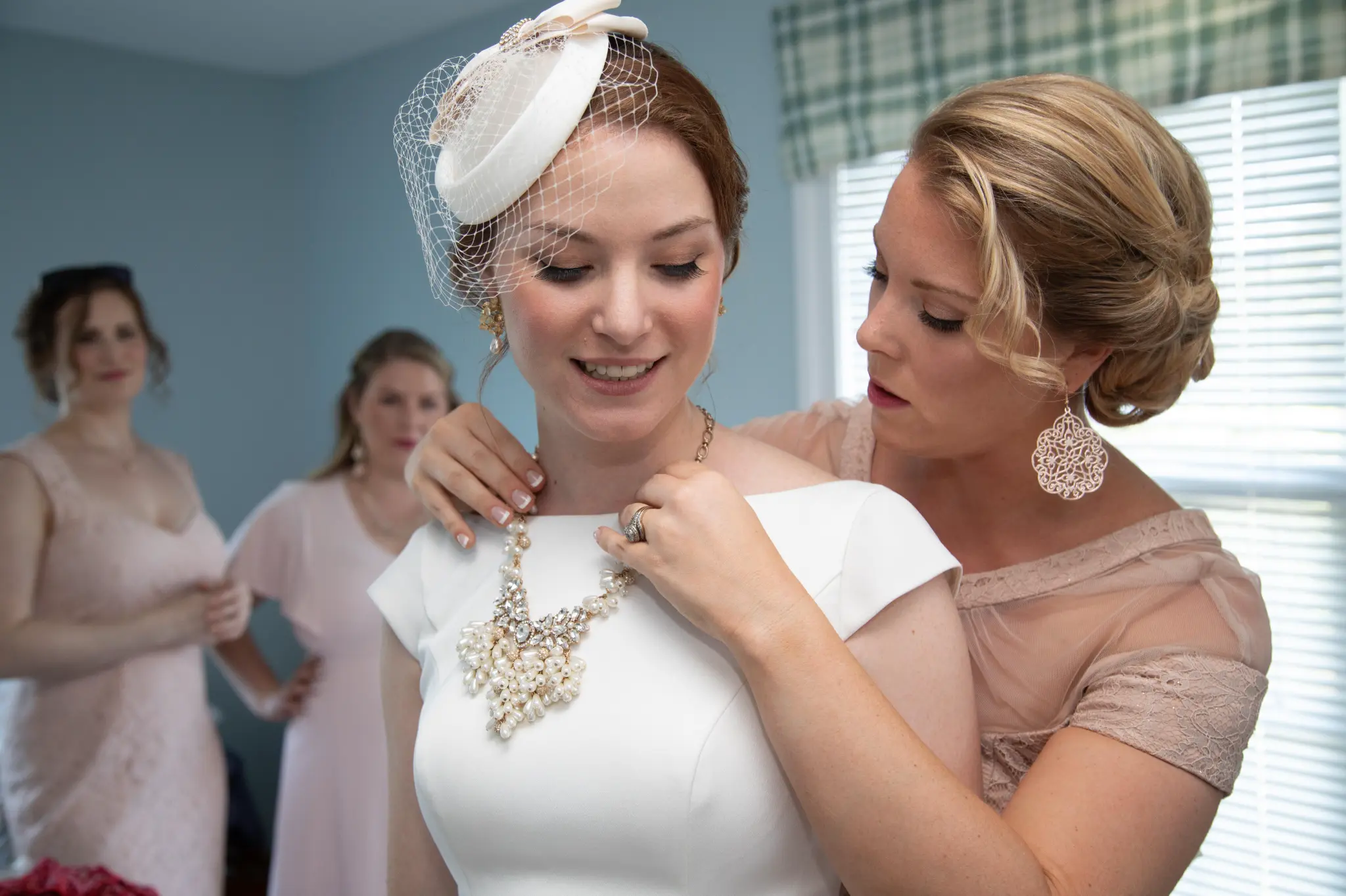 Bridesmaid fastening Emily's necklace before the ceremony