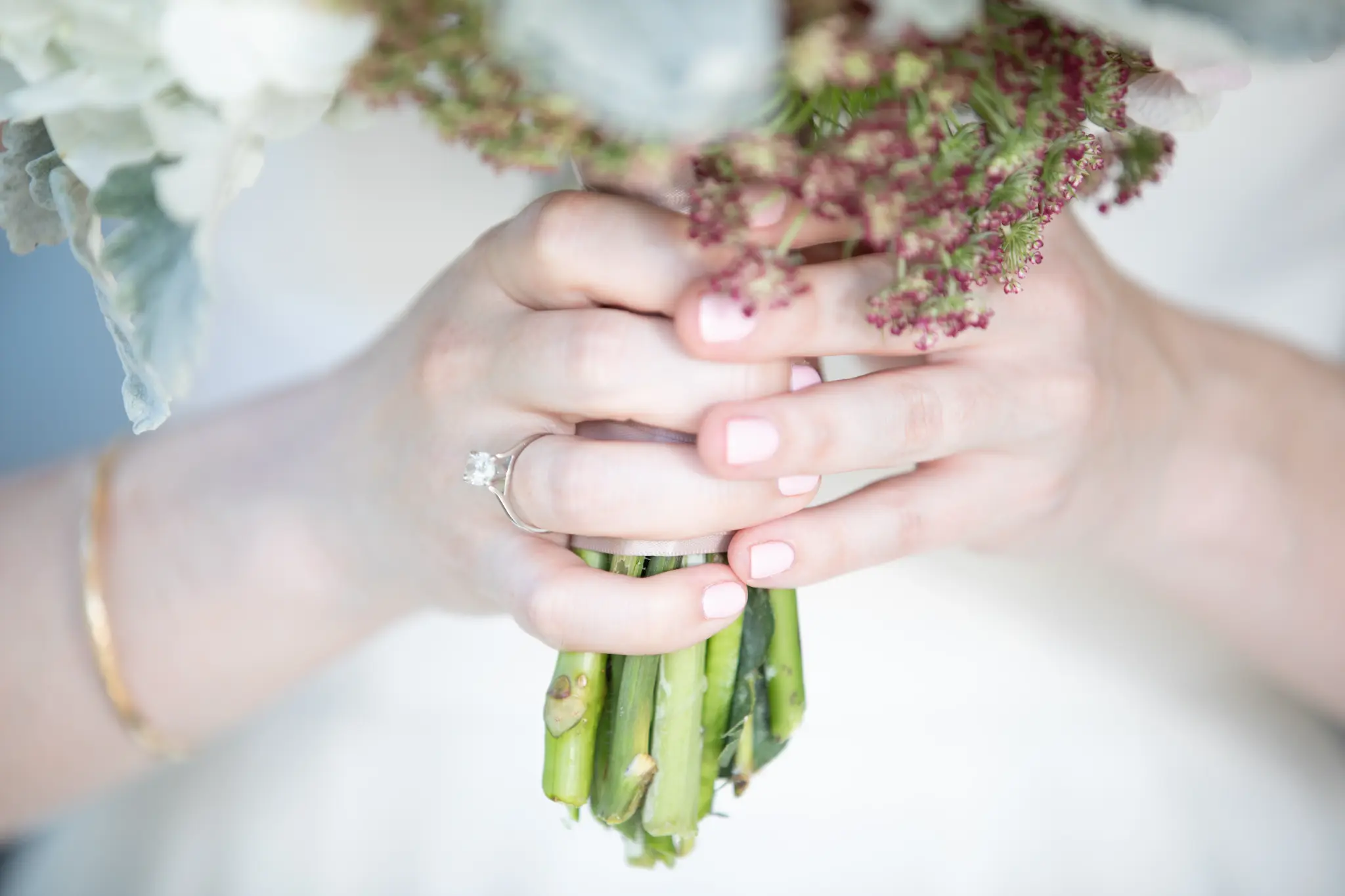 Bride's hands holding bouquet with engagement ring