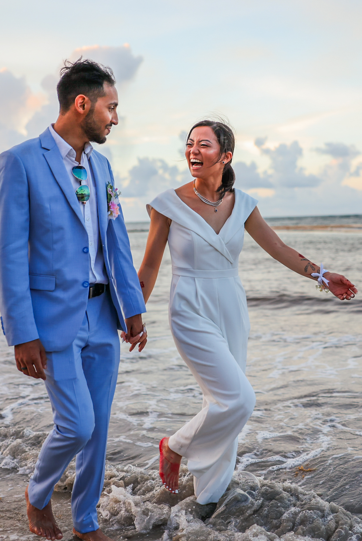 Couple laughing and walking barefoot through Caribbean waves