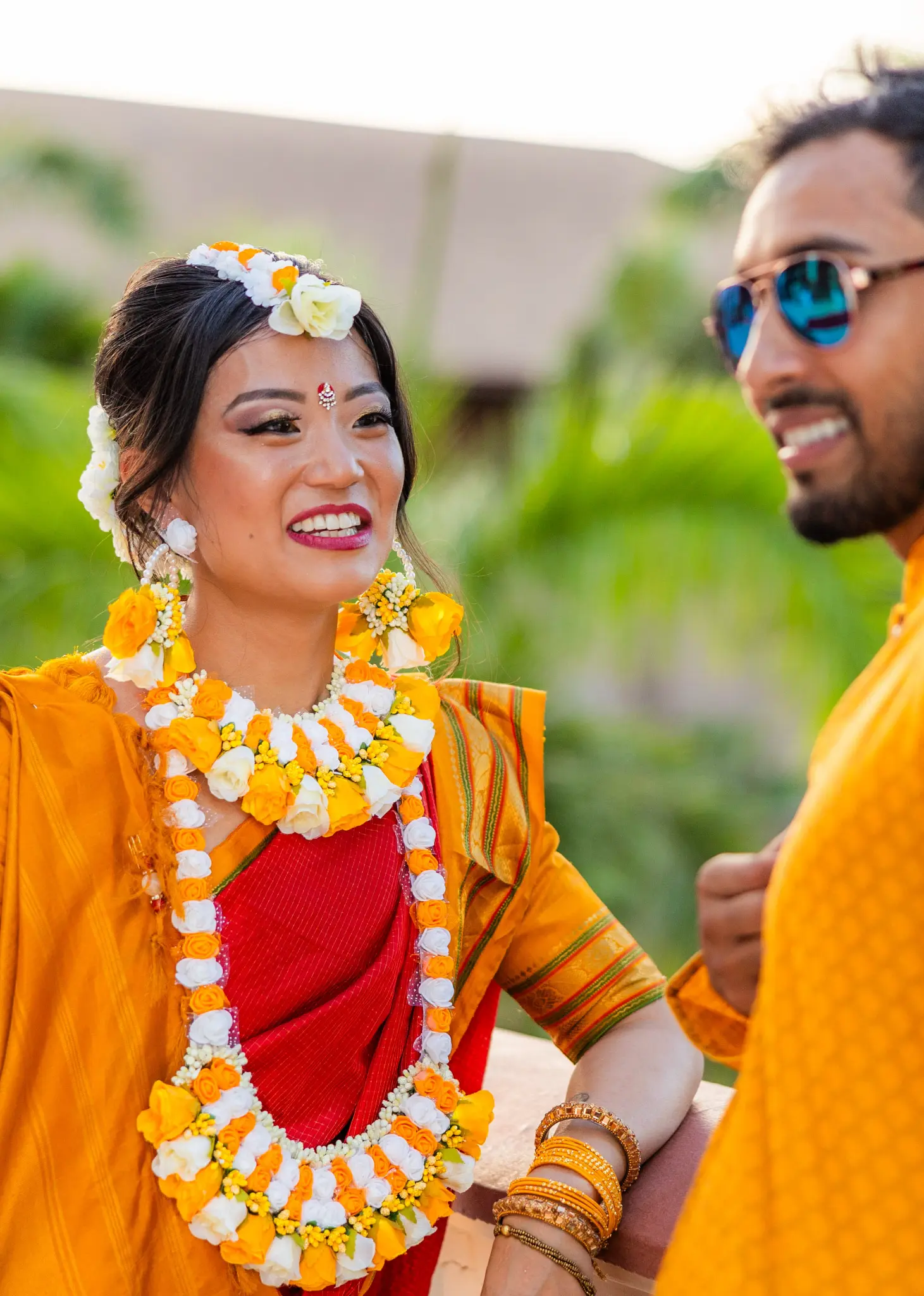 South Asian bride in marigold garlands laughing with groom at Haldi ceremony — Andrew Rozario multicultural wedding photographer